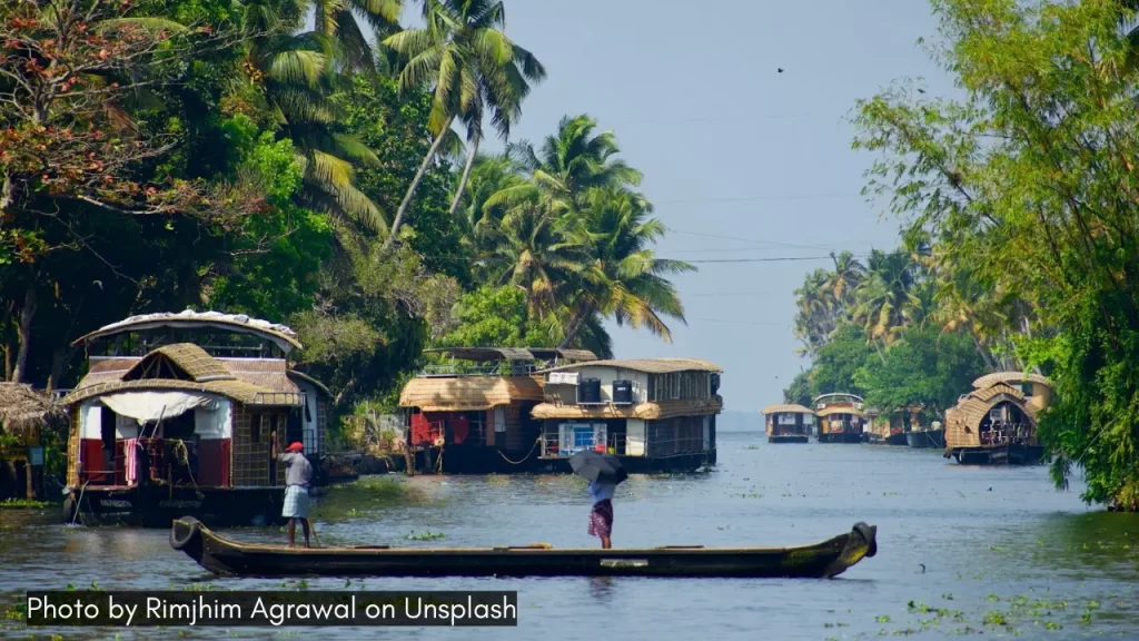 Houseboats on the backwaters of Alleppey, Kerala, one of the best places to visit in December in India, surrounded by lush greenery and palm trees.