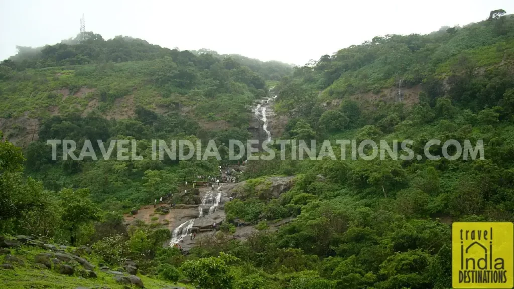 Hill behind Bhushi Dam with flowing streams and people climbing up to enjoy the monsoon experience.