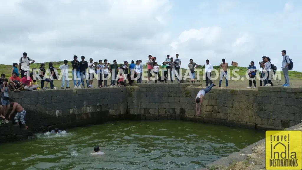 A group of people swimming in one of the wells at the Lohagad Fort after trek.