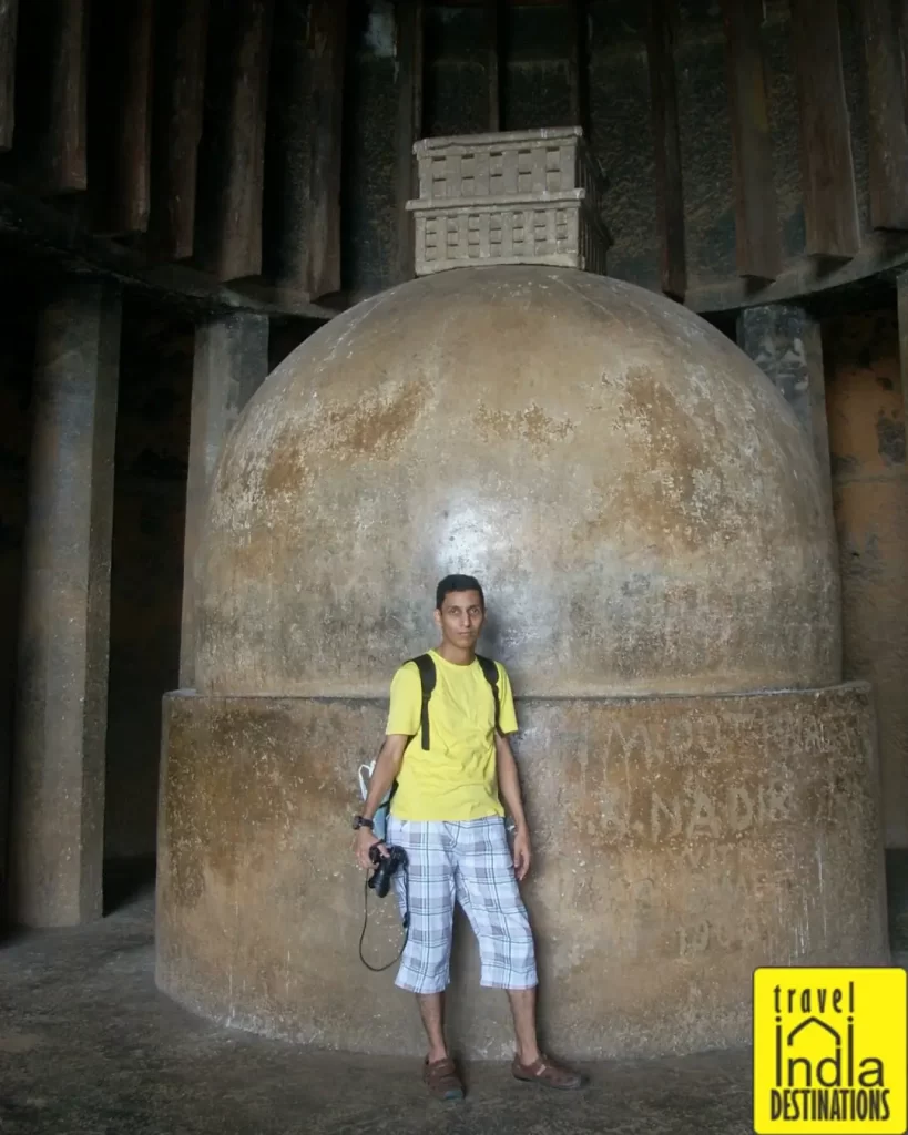 Sharukh standing with a camera near the stupa at the end of the Chaitya Hall in Bhaja Caves.
