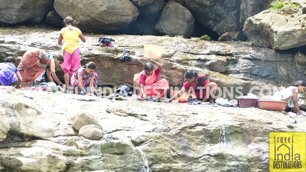 women washing clothes on the rocks at Bhaje village
