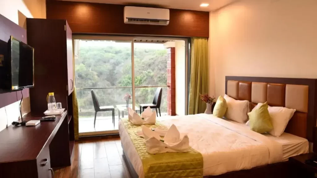 Bedroom at Khushi Riverside Mahabaleshwar with balcony seating and flat-screen TV