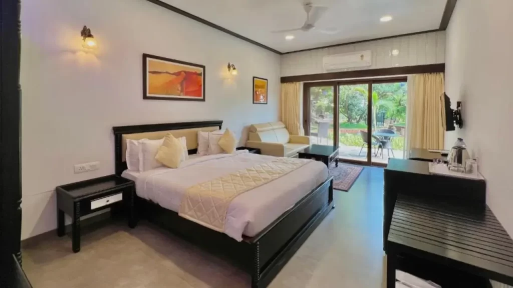 Spacious room at Tranquil Resort & Spa Mahabaleshwar with king-size bed, window-side sofa, and balcony seating one of the best hotels in Mahabaleshwar for couples