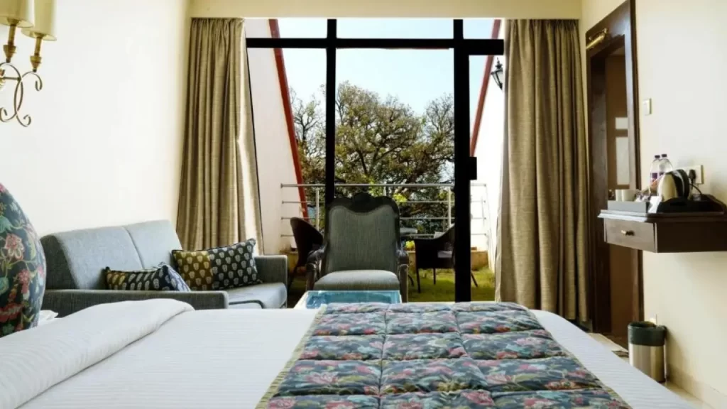 Room at Valley View Beacon Resort Mahabaleshwar with king-size bed, window-side seating, and balcony chairs