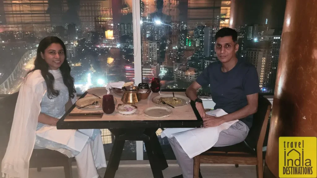 Couple having dinner at Kangan restaurant at Westin Mumbai Garden City with night cityscape in the background.