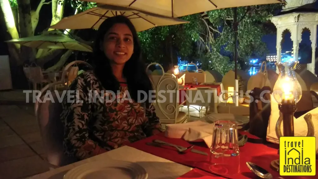 A shot of a woman enjoying dinner experiences at Tribute Restaurant in Udaipur under candlelight.