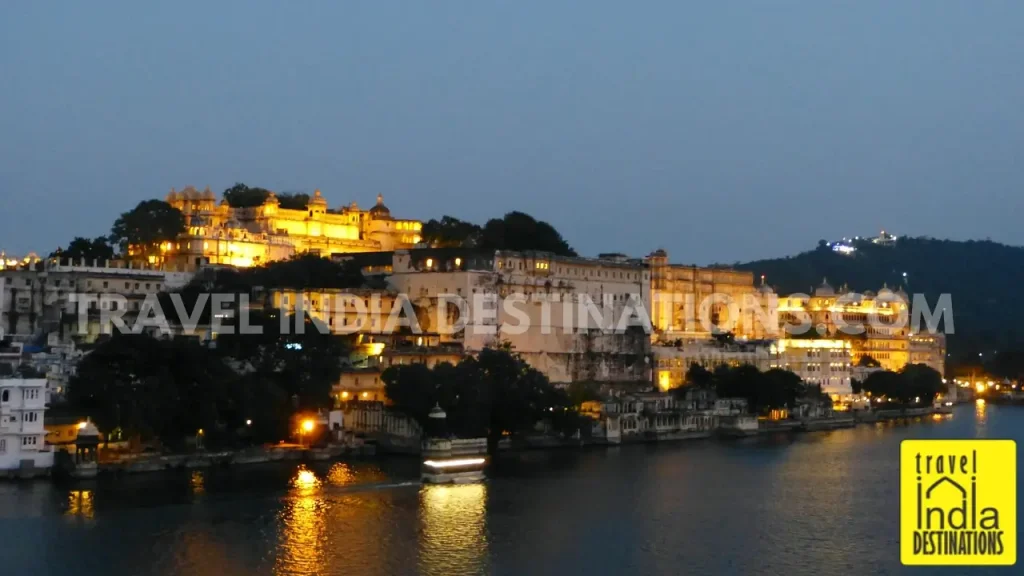 A picture of City Palace Udaipur with the evening golden lights on across Lake Pichola.
