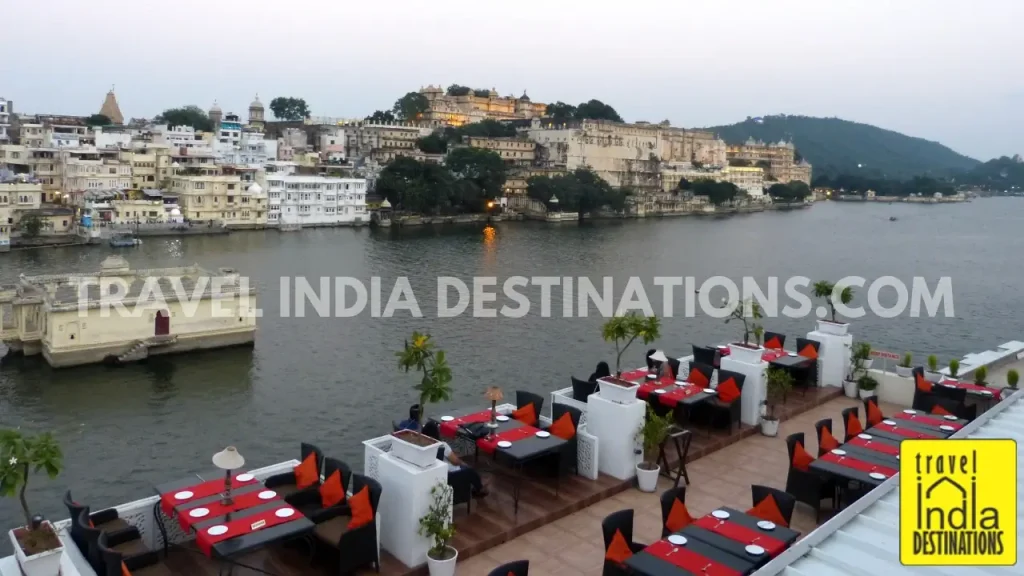 A shot of deck tables at Upre by 1559 AD overlooking Lake Pichola and the City Palace just before the golden hour.