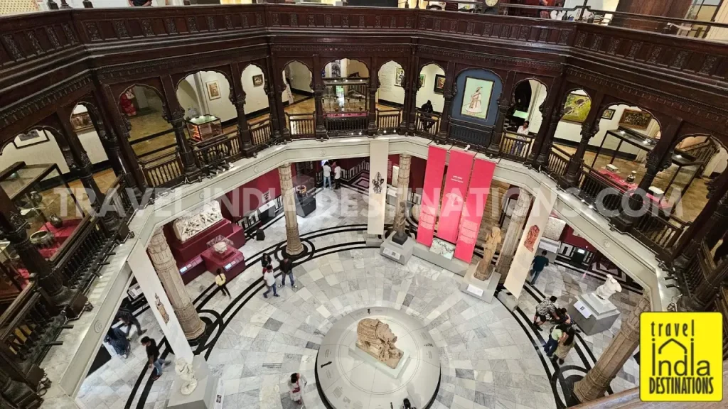 Wide-angle view of the Rotunda Gallery at CSMVS from the second floor showing the central sculpture, wooden railings, arches, and the floor design.