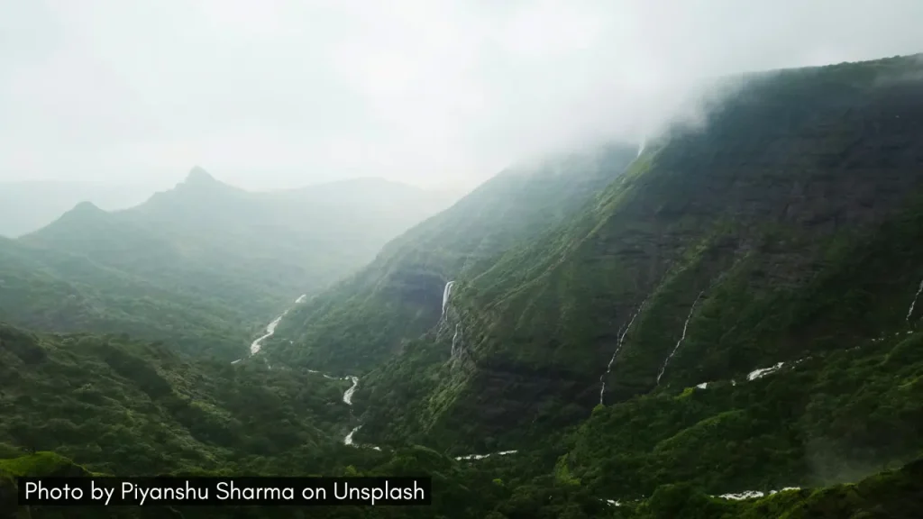 A wide-angle shot of Bhandardara during the monsoon season with mist-filled valley and river streams.