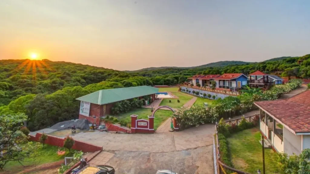 An overview of villas at Forest County Resort in Mahabaleshwar with surrounding lush green hills and sunset.