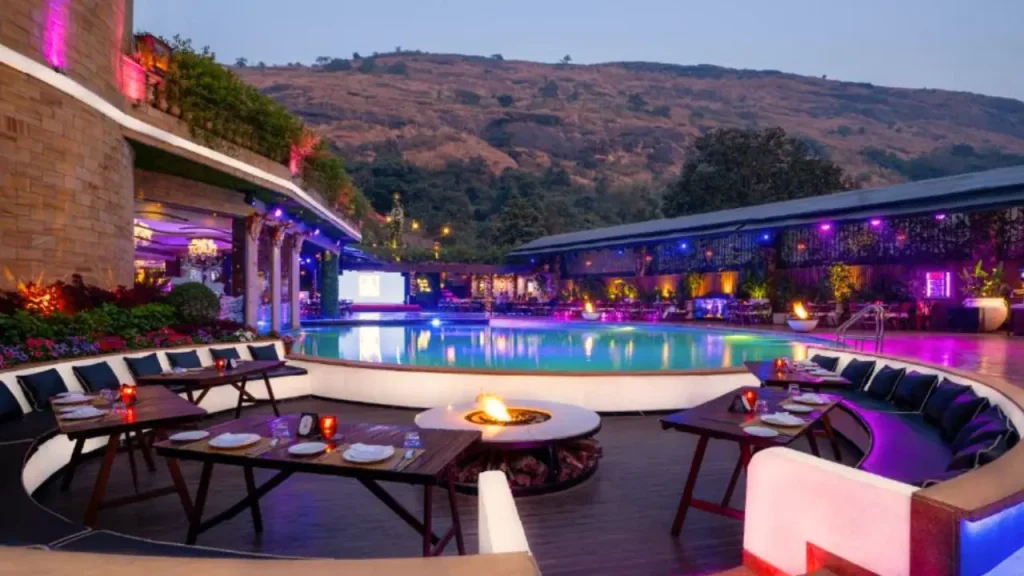 A shot of outdoor swimming pool and sitting arrangement at Della Resort, one of the luxury resorts in Lonavala.