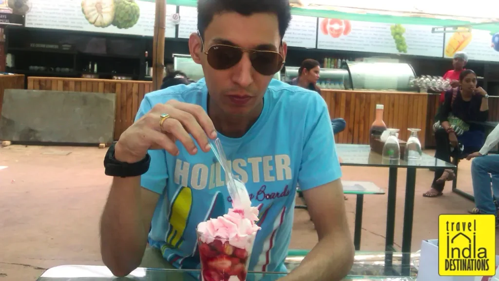 A man enjoying strawberry milkshake at Mapro Garden in Mahabaleshwar, one of the best places to visit.