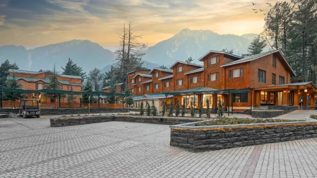 Exteriors of Radisson Golf Resort in Pahalgam with surrounding snow-capped mountains and trees ideal for minimoon in June.