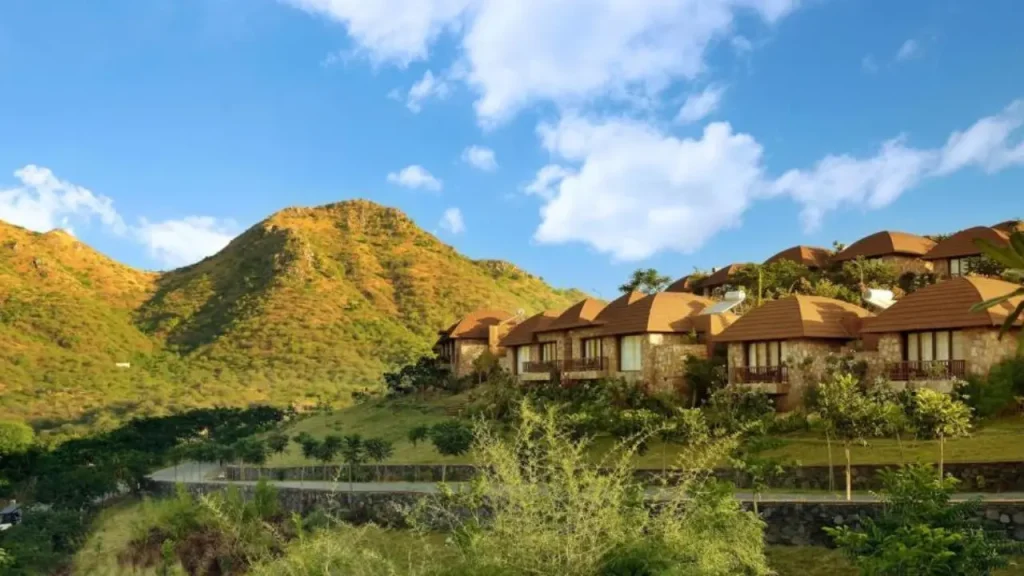 A shot of The Ananta five-star luxury hotel in Udaipur with surrounding hills and property cottages, one of the best family hotels in Udaipur.